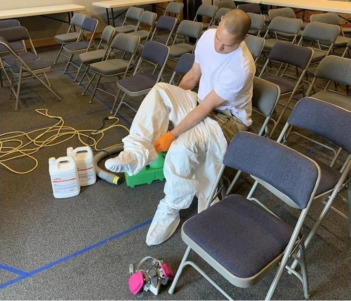 SERVPRO Tech putting on PPE to disinfect building