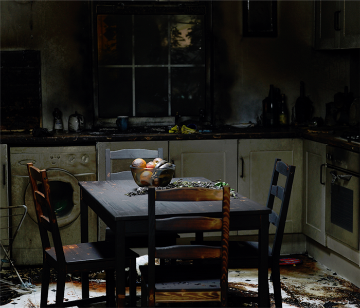 a fire damaged kitchen with soot covering the walls and tables